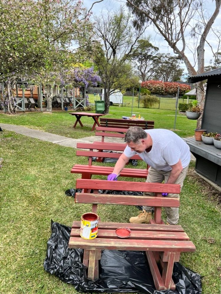 Scott sands down and paints a bench in the outdoor recreation area of the RG Centre.